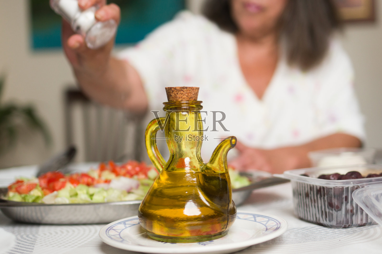 不认识的女人在给食物加盐。营养中的盐滥用。照片摄影图片