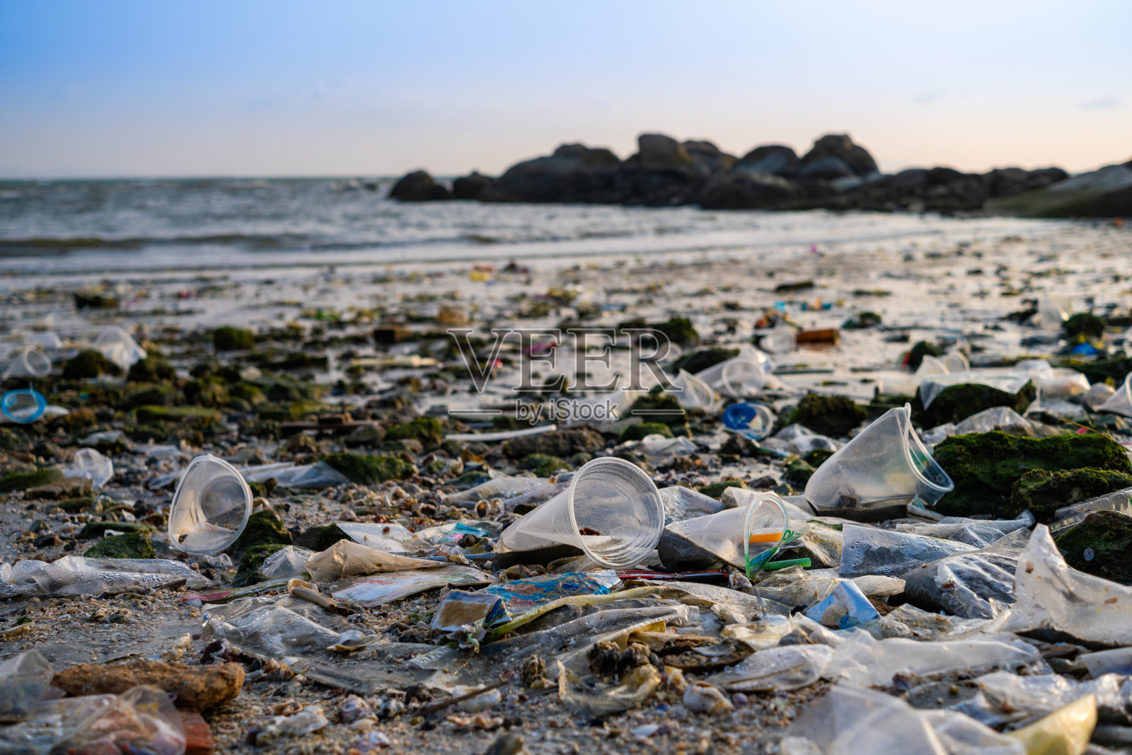 海滩碎片，塑料杯和塑料袋。海洋垃圾是世界上主要的环境问题之一。照片摄影图片