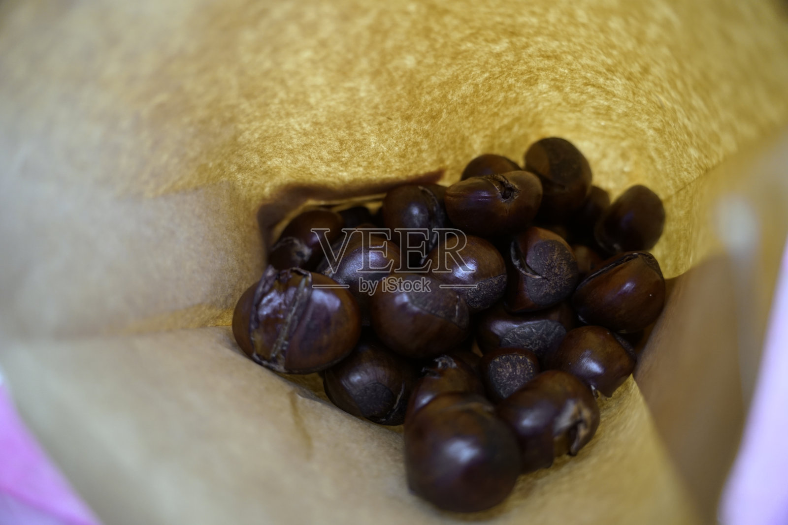 从街头小贩那里买来的烤栗子装在纸袋里照片摄影图片