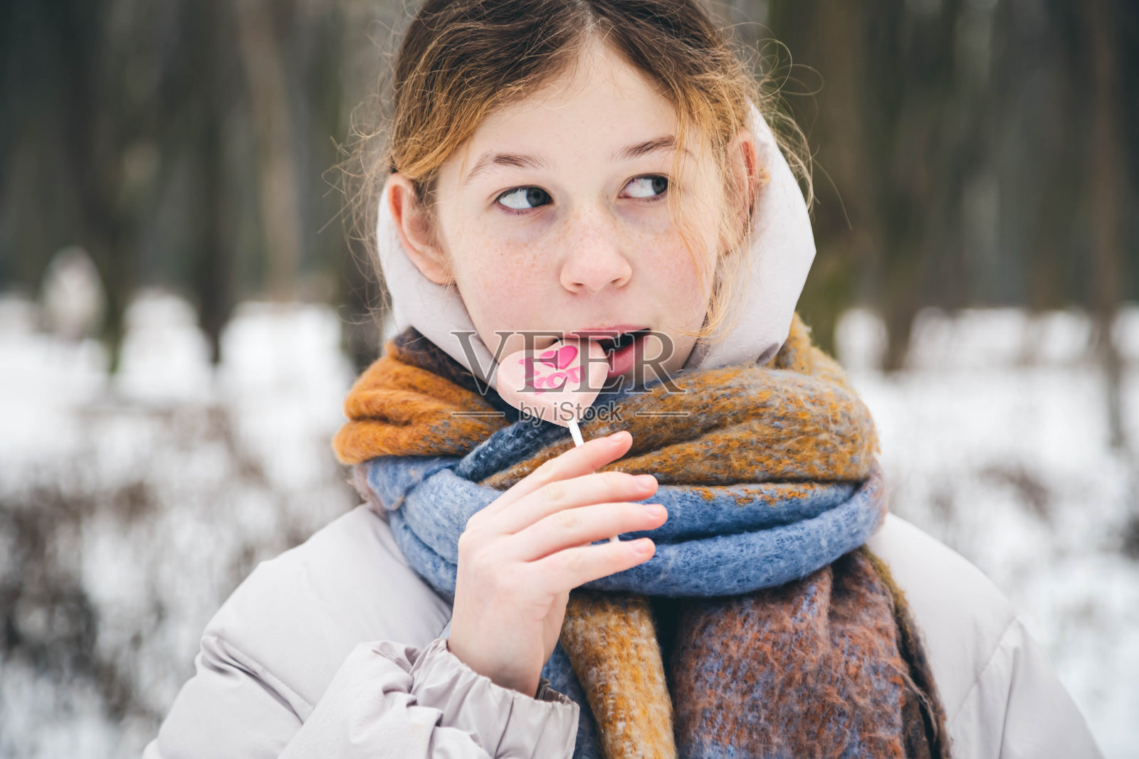 女生吃心形棒棒糖，情人节概念。照片摄影图片