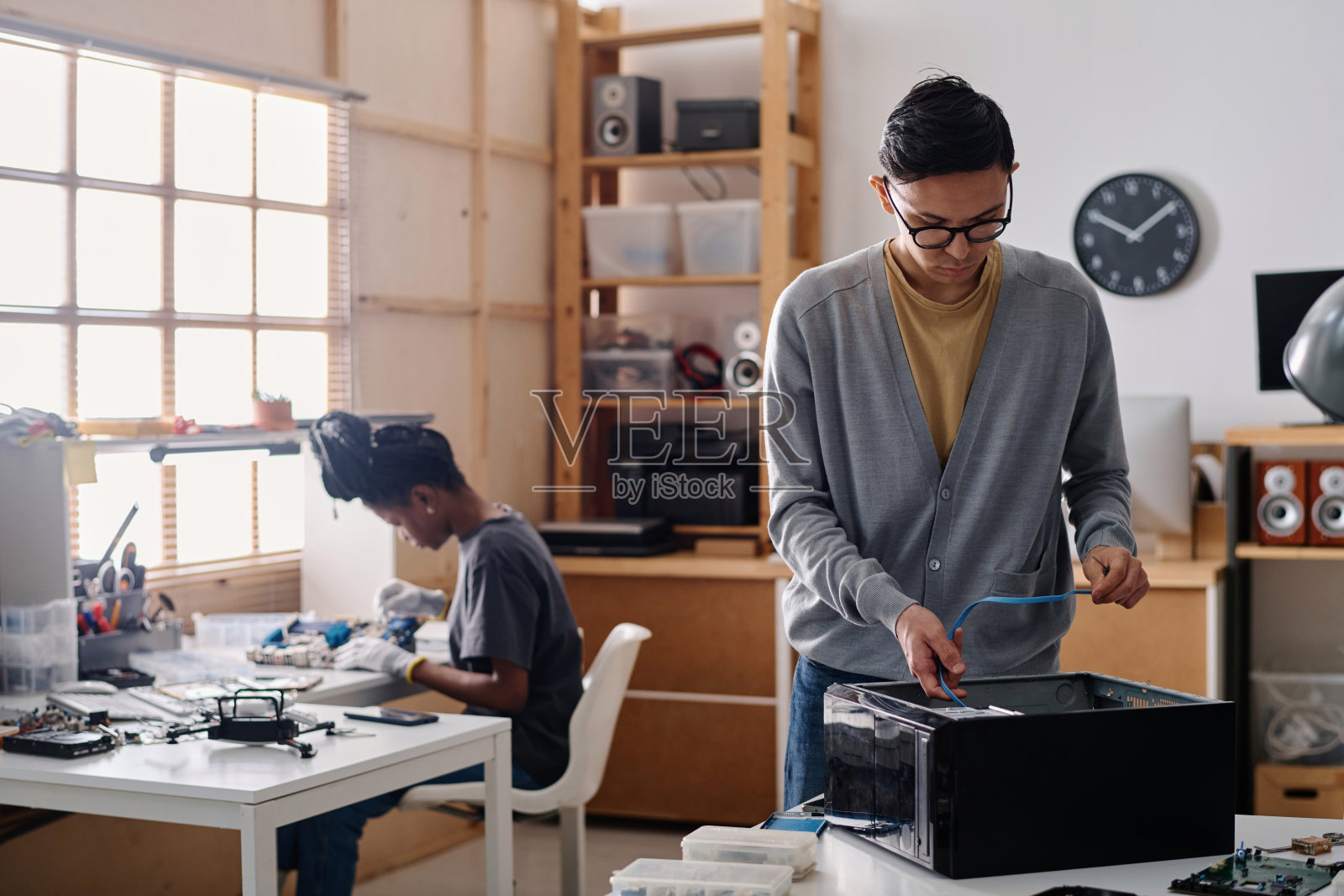 混血儿同事在车间里并肩修理电子设备照片摄影图片