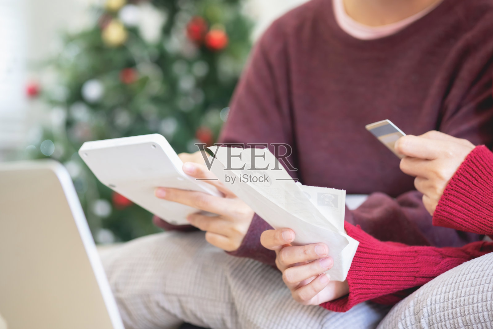 一位年轻的亚洲女子坐在家里的沙发上，对每月的开支感到担忧和沮丧。各种水电费账单。照片摄影图片