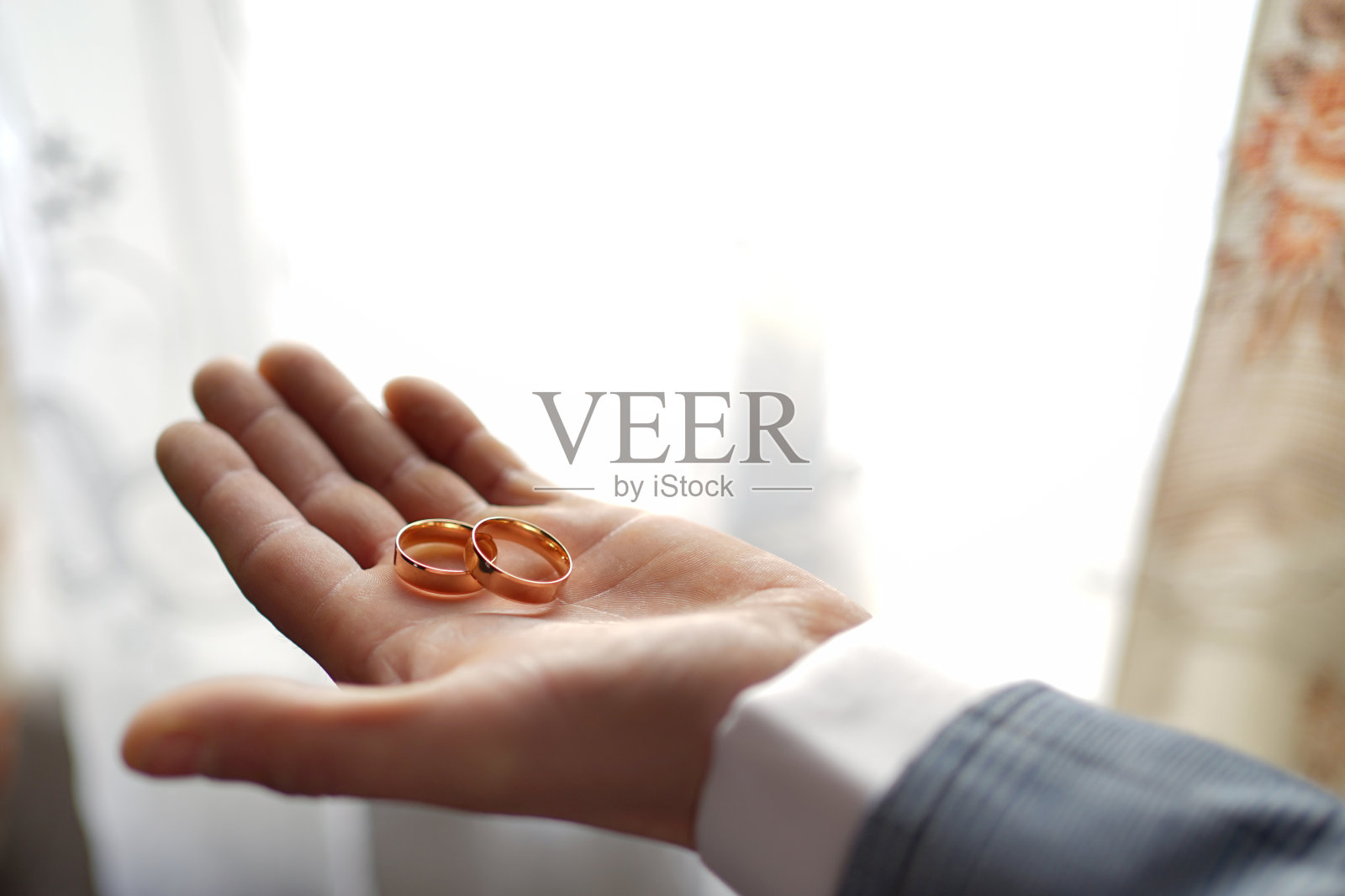 男人手持两枚金色结婚戒指，婚礼仪式照片摄影图片