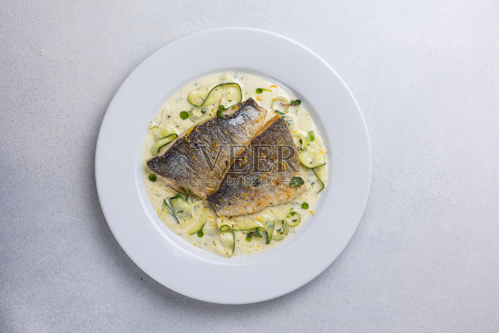 白色盘子里的烤鱼配西葫芦和莳萝照片摄影图片