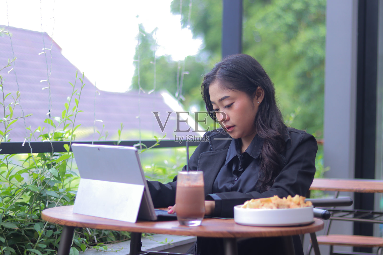 穿着办公室装的亚洲美女在咖啡厅里一边吃一边做作业照片摄影图片