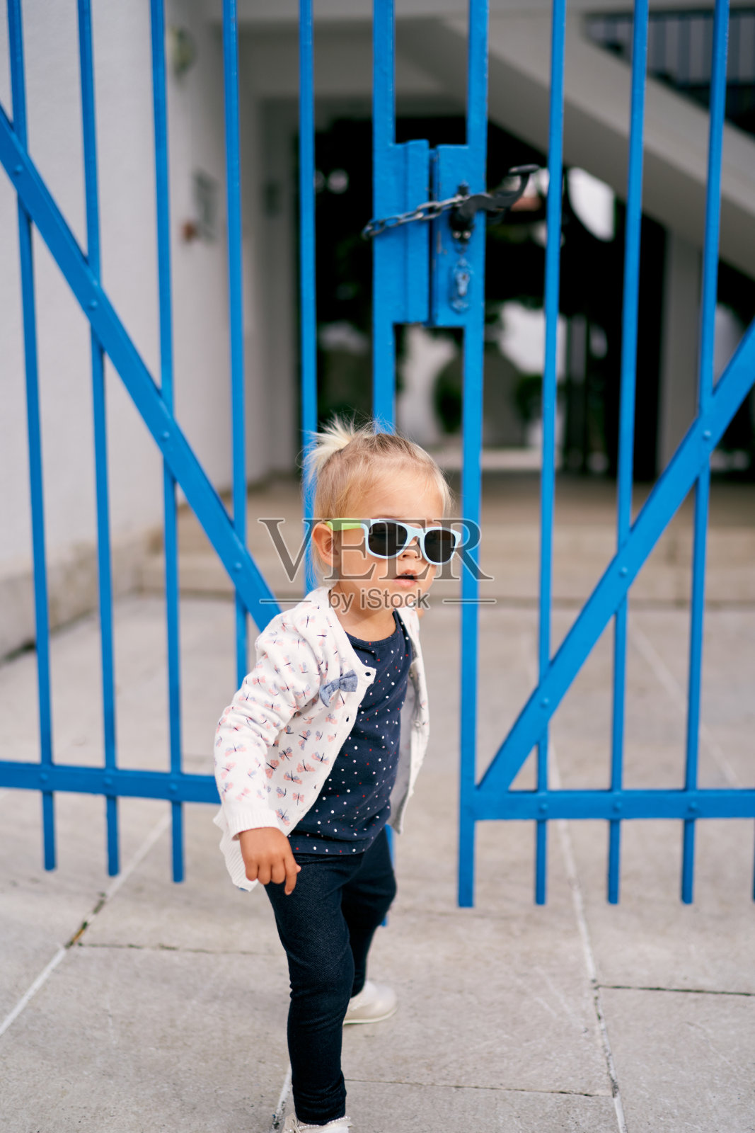 小女孩站在房子的铁门附近照片摄影图片