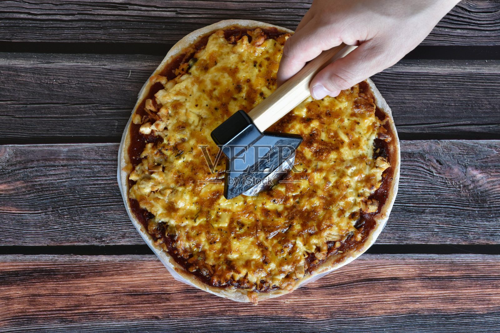 用特制的刀切新鲜出炉的自制披萨。照片摄影图片