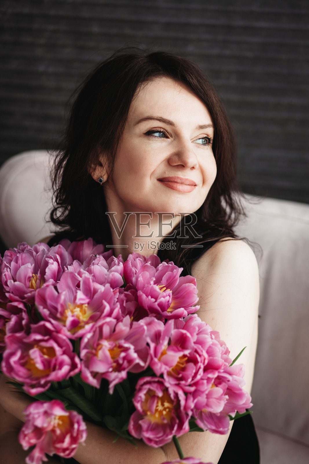 一个女人拿着一束牡丹的画像。照片摄影图片