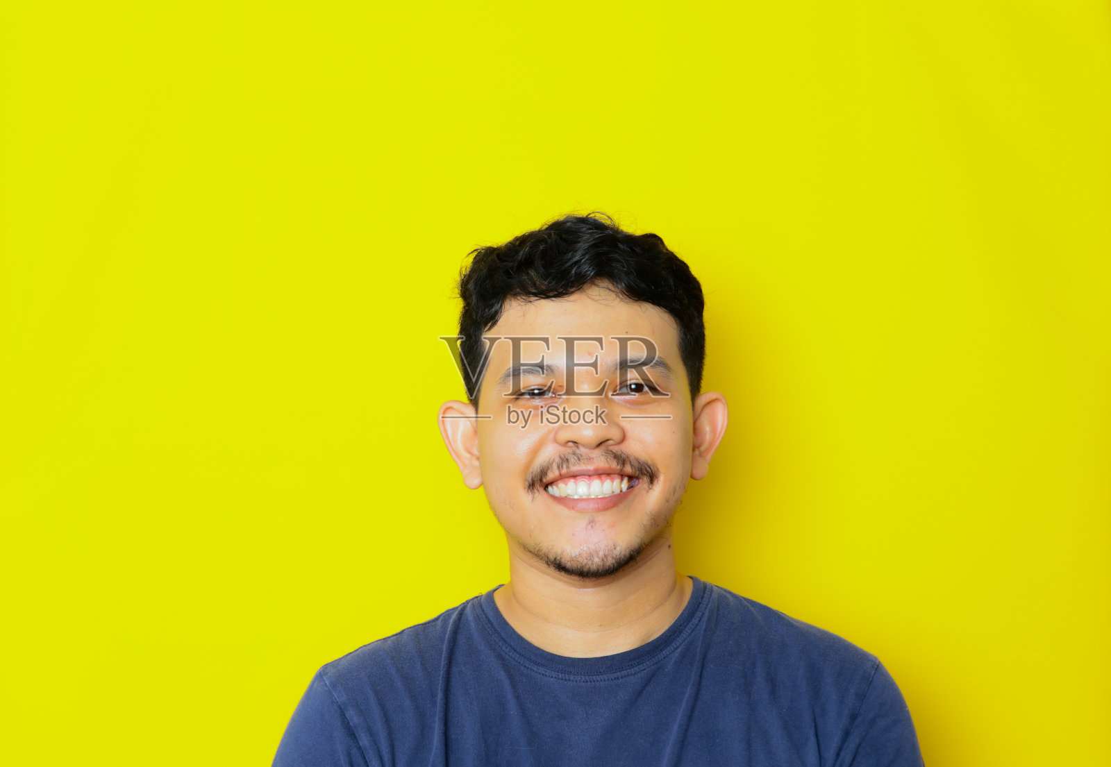 摄影棚里拍摄的一幅孤独微笑的亚洲年轻人的肖像。广告的概念。照片摄影图片