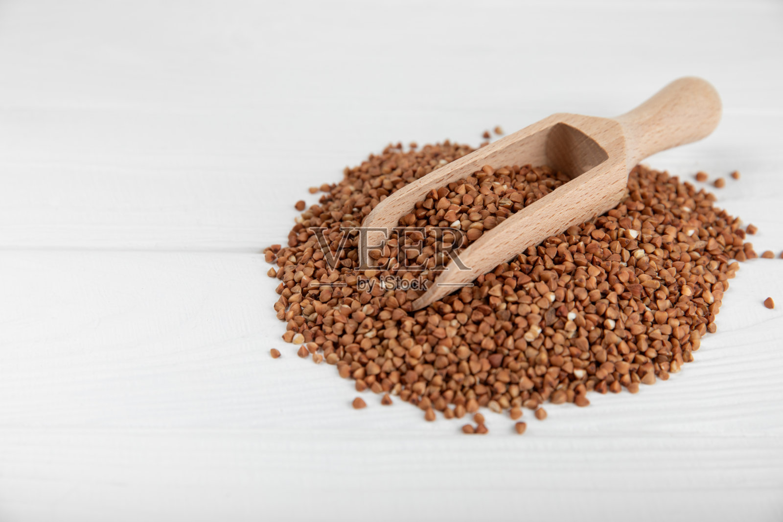 生荞麦放在有纹理背景的碗里。麦粒，粥，谷物，生荞麦在一个盘子里。健康食品。粥。饮食。有机屈曲。文本空间。副本的空间。照片摄影图片