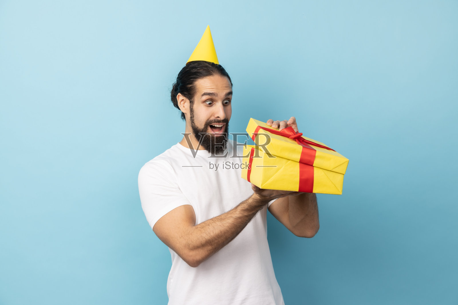 戴派对帽的男人打开礼物盒，面露惊讶表情照片摄影图片