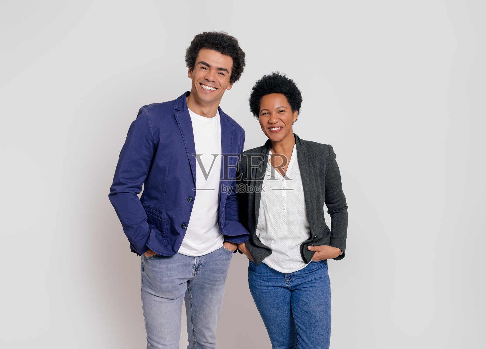 欢快的年轻伴侣的肖像，双手插在口袋里，微笑着站在白色背景上照片摄影图片