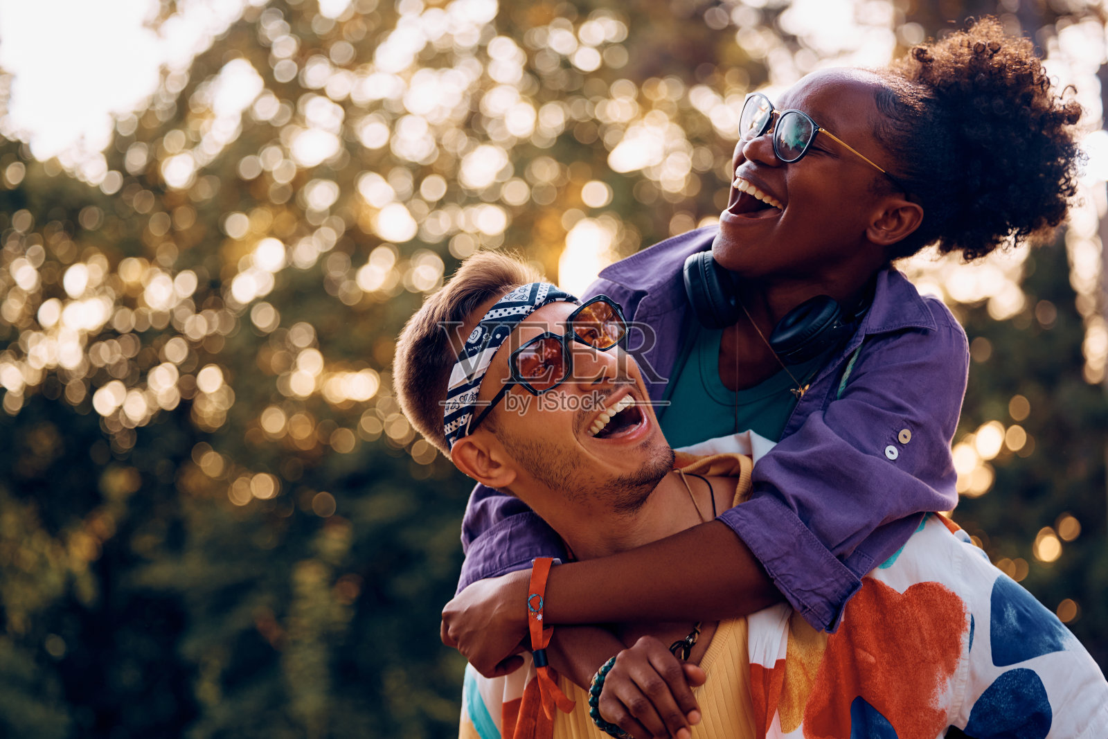 一个快乐的男人背着他的黑人女友去参加夏季音乐节。照片摄影图片