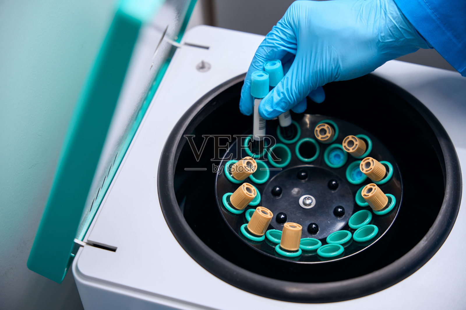 实验室工作人员将装有生物材料的试管放入专用仪器中照片摄影图片