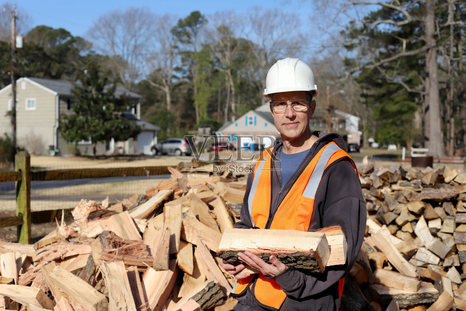 一个为树艺师工作的人站在他的一堆木头前。照片摄影图片