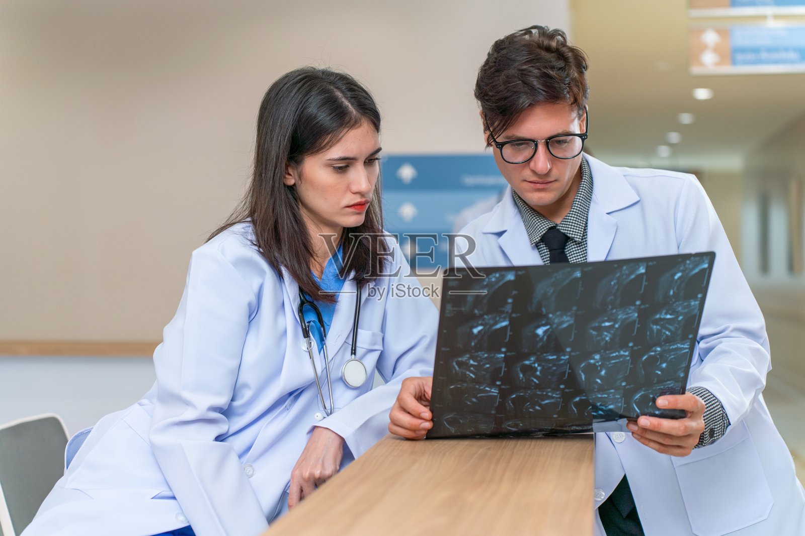 诊断合作:白人男性和多种族女性医生分析病人x光片照片摄影图片