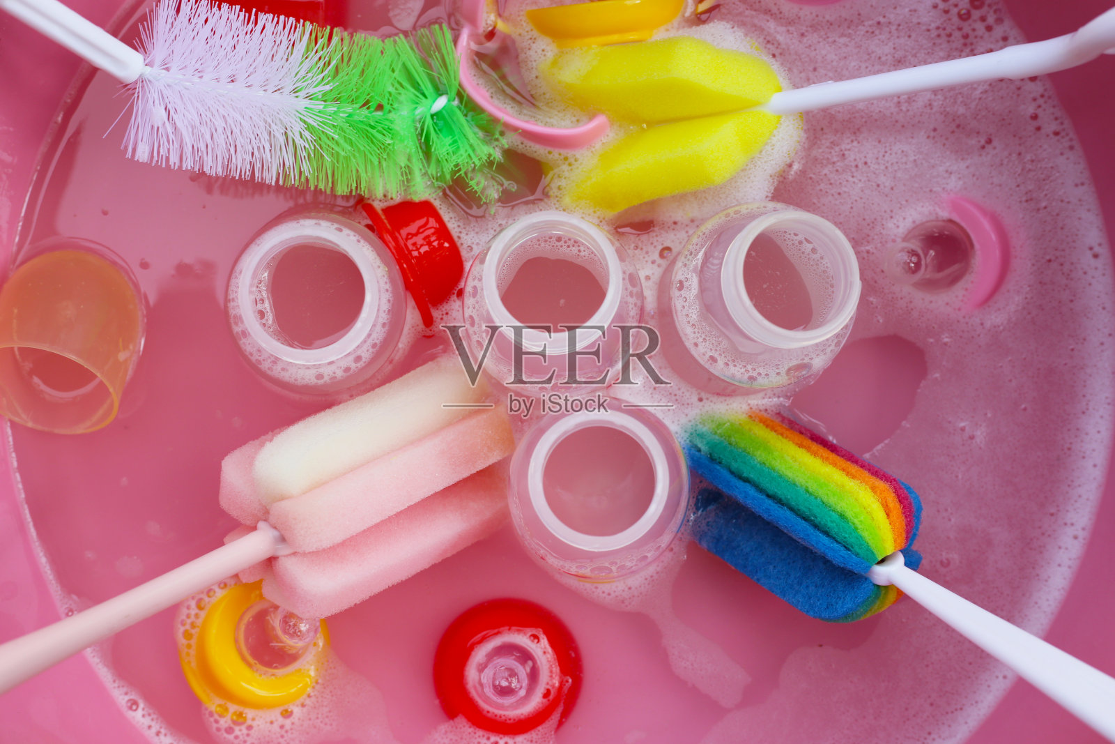 用粉红色的塑料盆洗奶瓶照片摄影图片