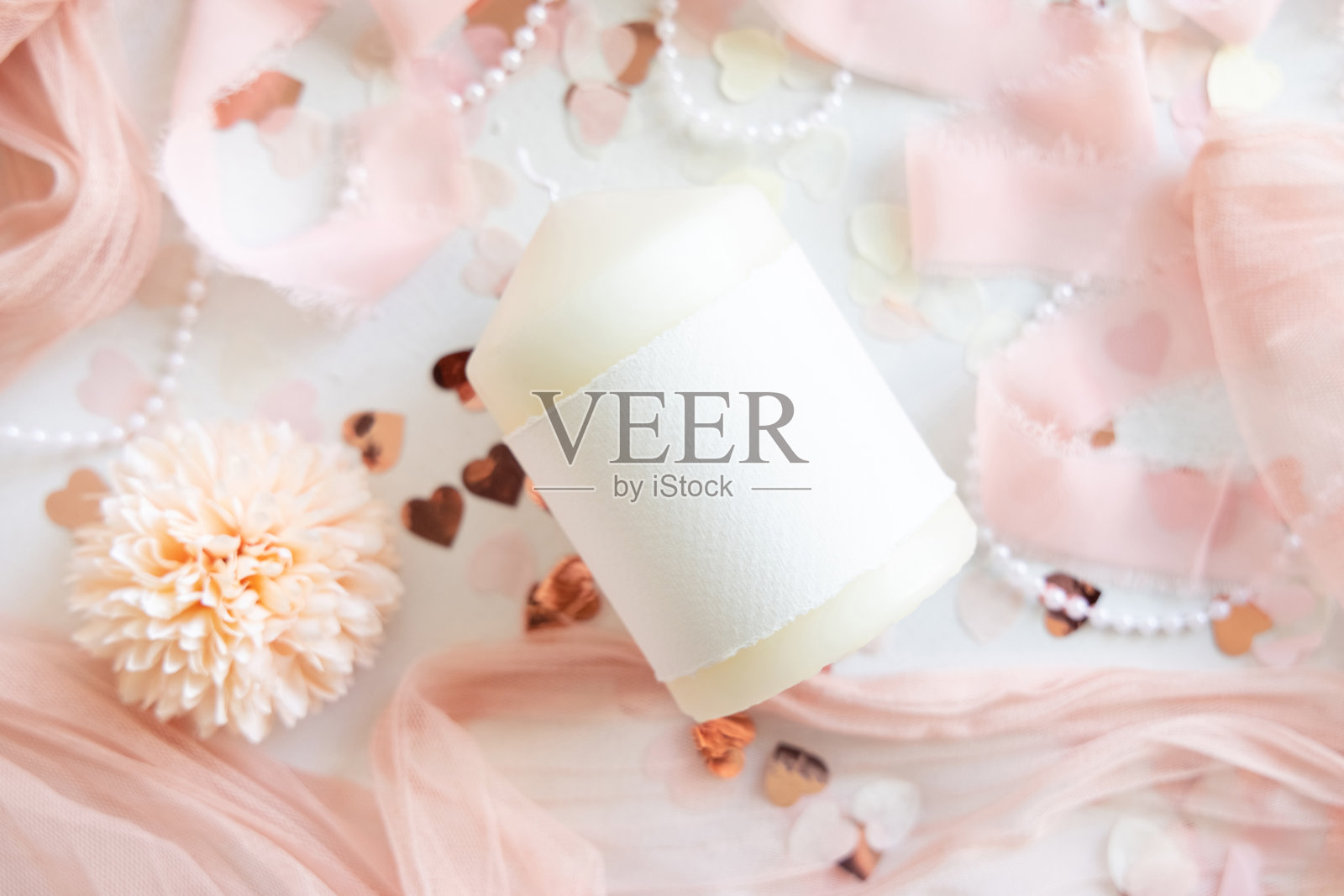 粉色装饰旁带有空白标签的蜡烛，白色桌面上心形和薄纱俯视模型照片摄影图片