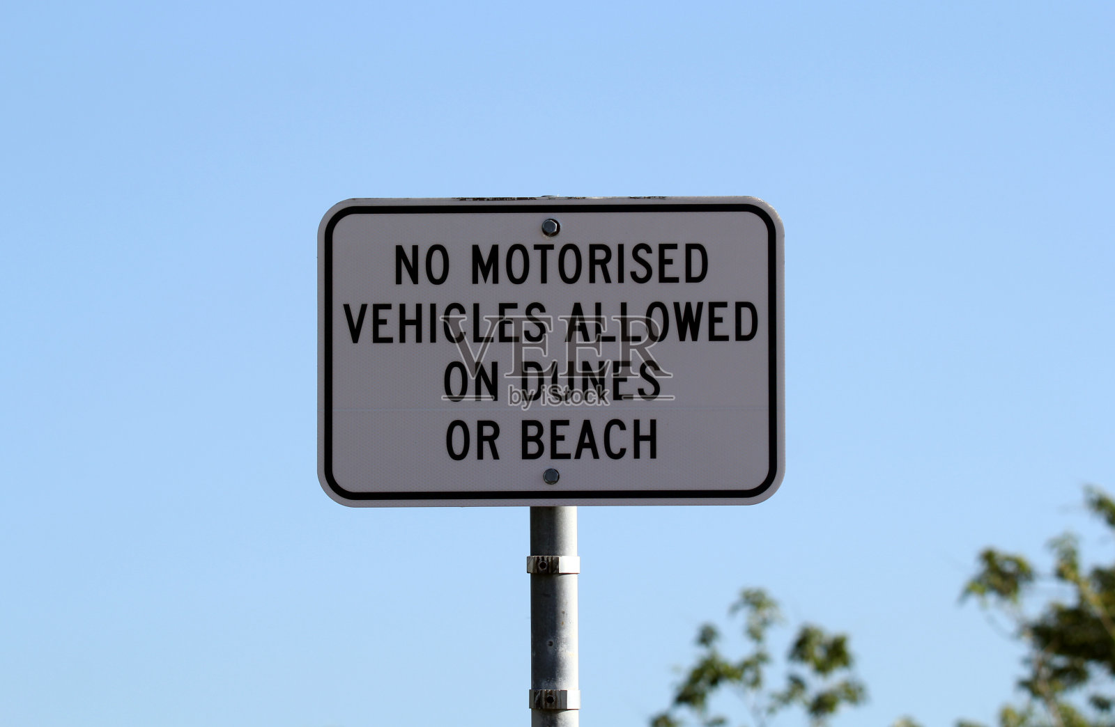 “沙丘和海滩上禁止机动车辆通行”的标志，背景是蓝色的天空照片摄影图片