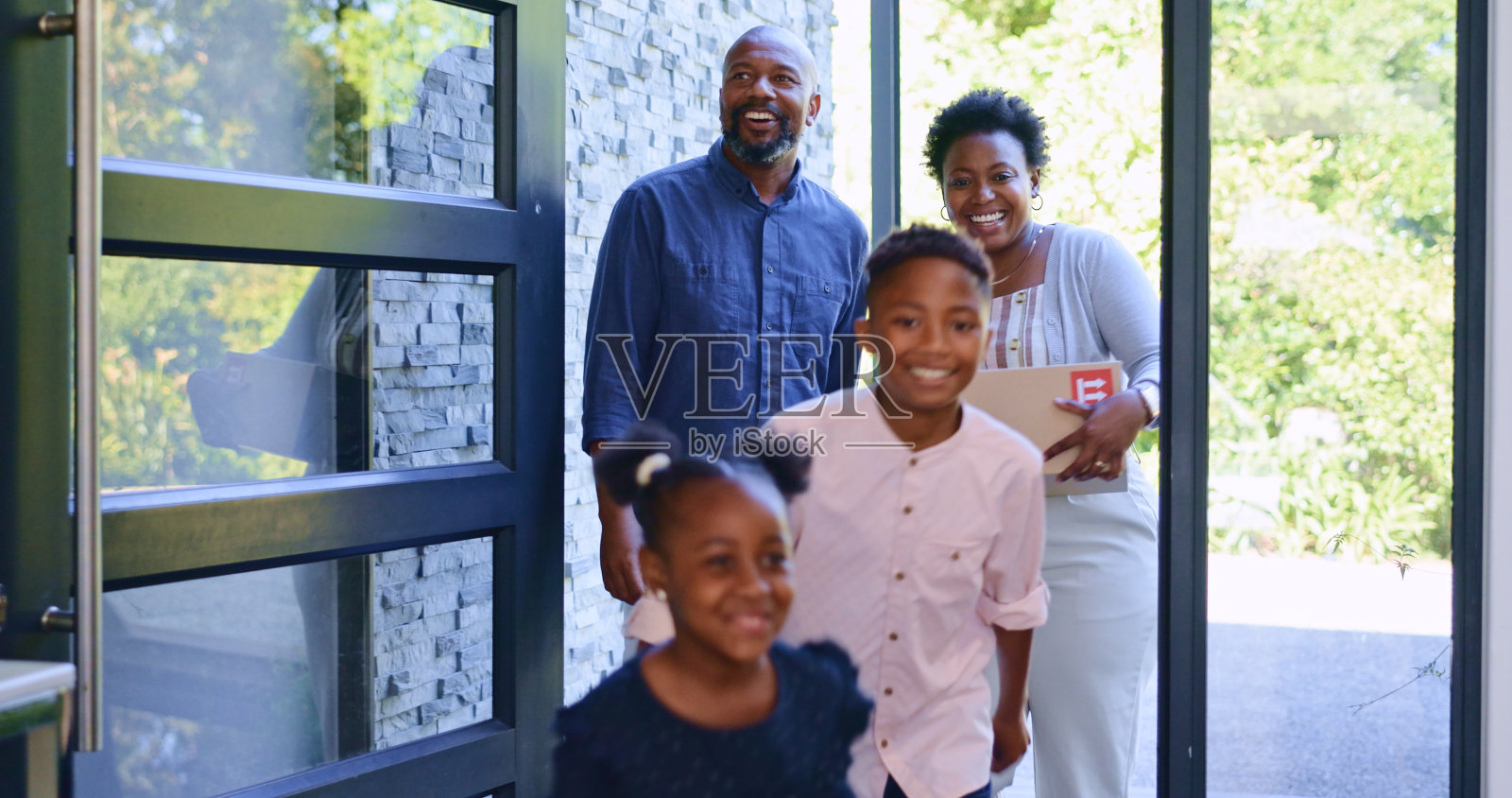 搬家的时候，黑人家庭带着孩子住进了新家，盒子和微笑摆在了房子的前门。妈妈，爸爸和快乐的孩子们在家里，兴奋的投资，房地产和未来在一起。照片摄影图片