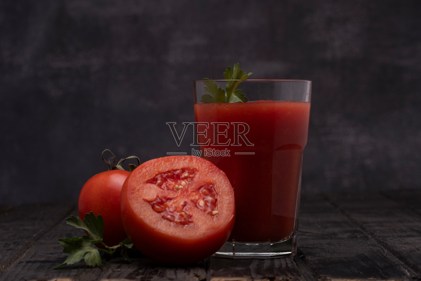 一杯新鲜番茄汁，配上西红柿，暗底配上欧芹。照片摄影图片