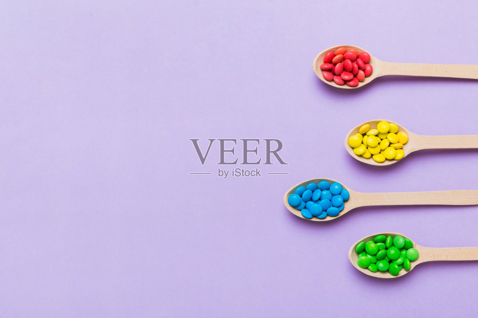 美味的彩色糖果勺子在彩色背景。糖果装饰顶视图与复制空间照片摄影图片