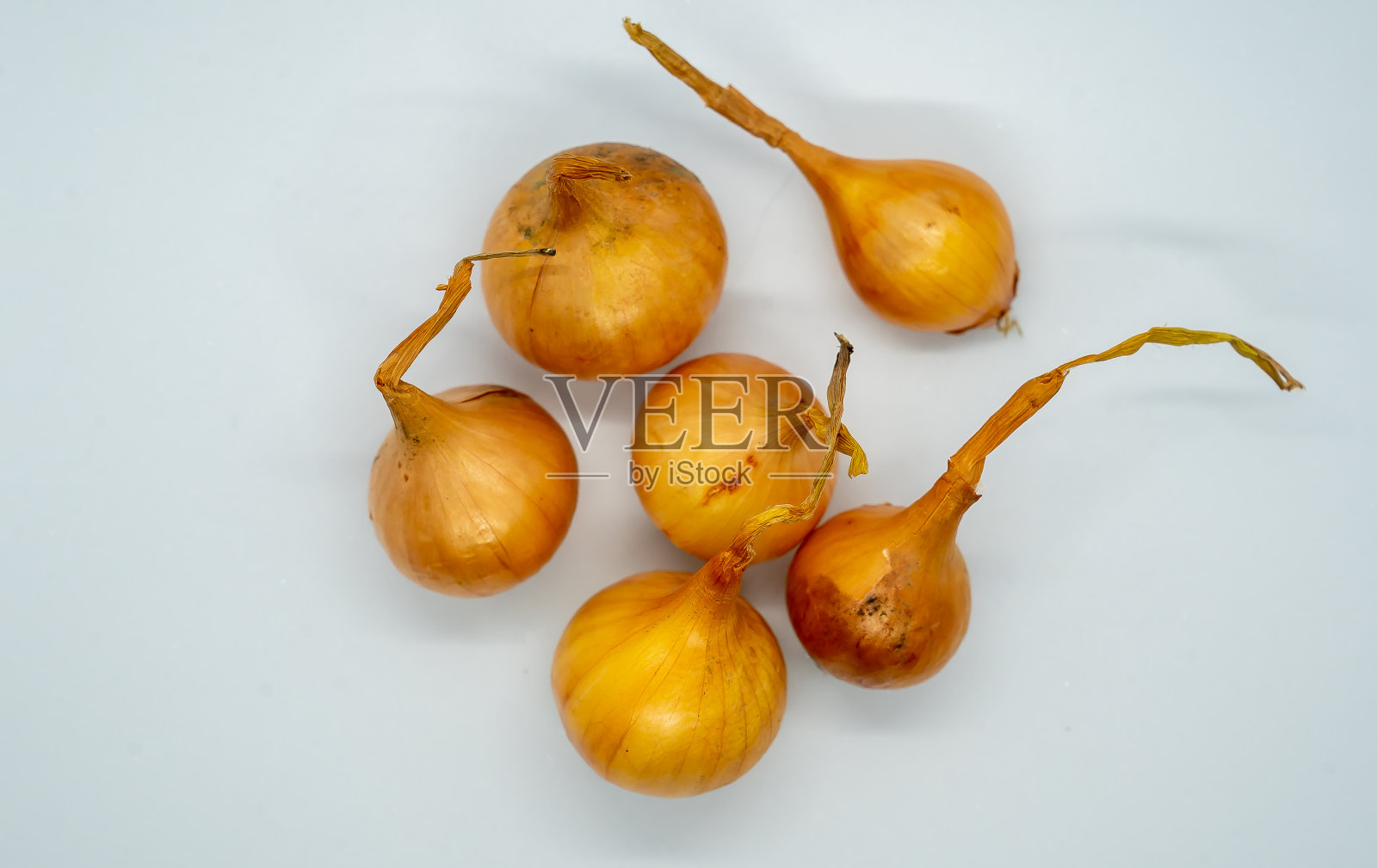 几个洋葱在一个白色的表面上，其中一个刚刚转动照片摄影图片