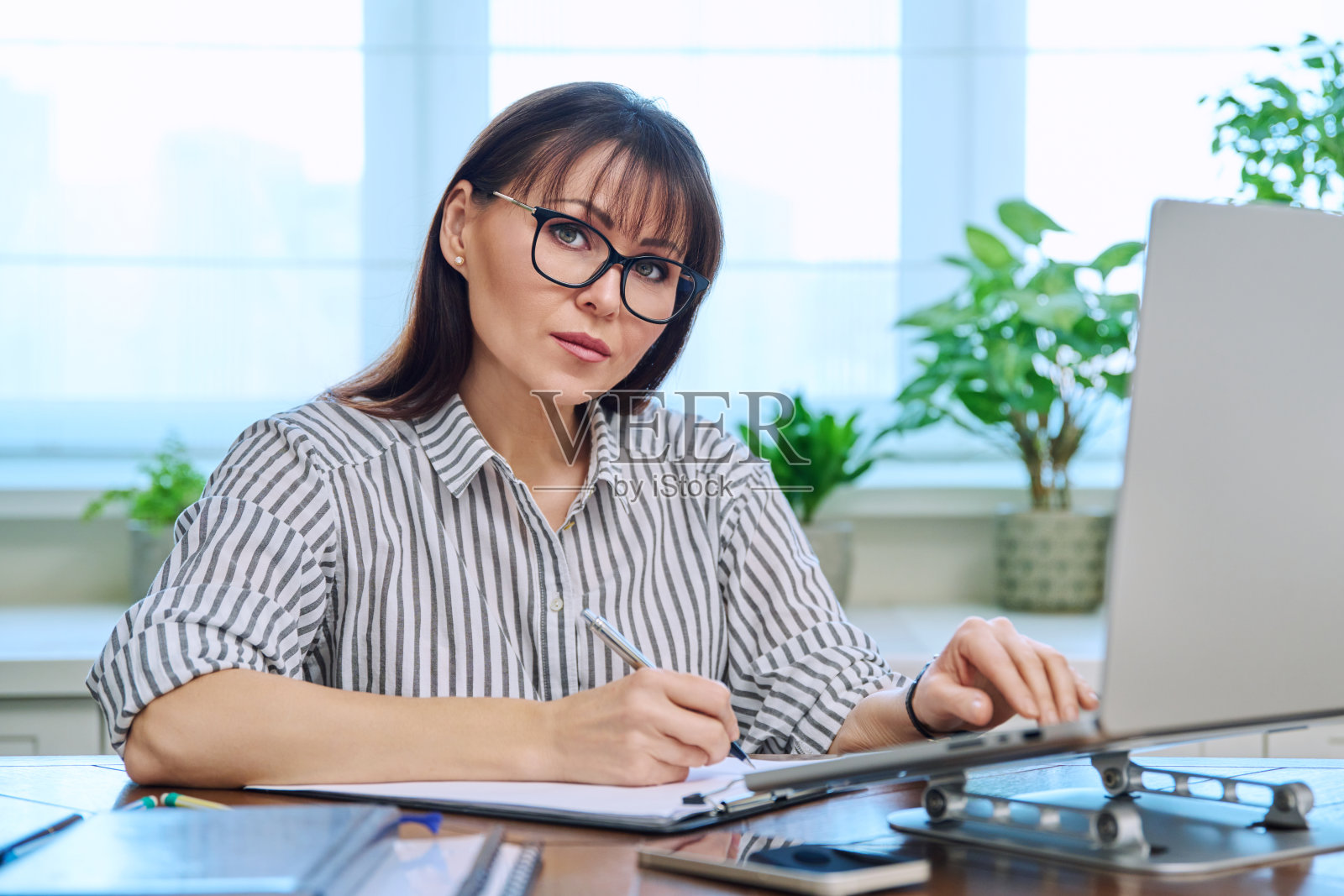 中年妇女的肖像在她的办公桌和电脑的工作场所照片摄影图片