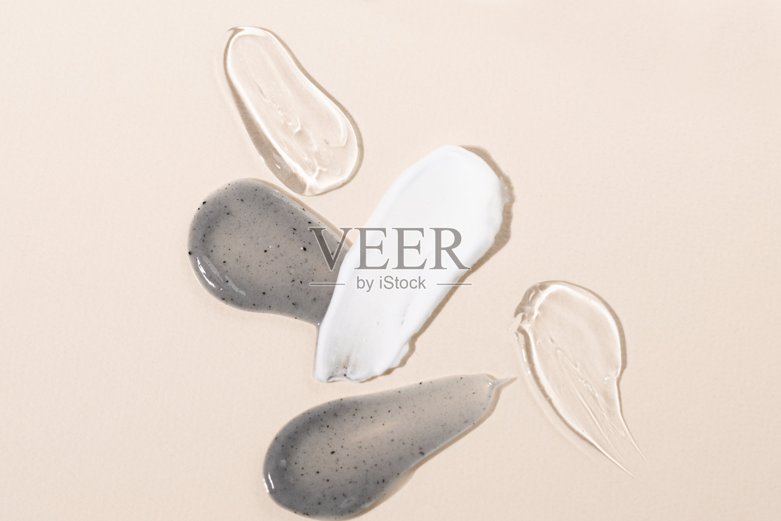 在米色背景顶部视图上涂抹化妆品纹理。炭面膜，体霜，凝胶，血清宏样品。照片摄影图片