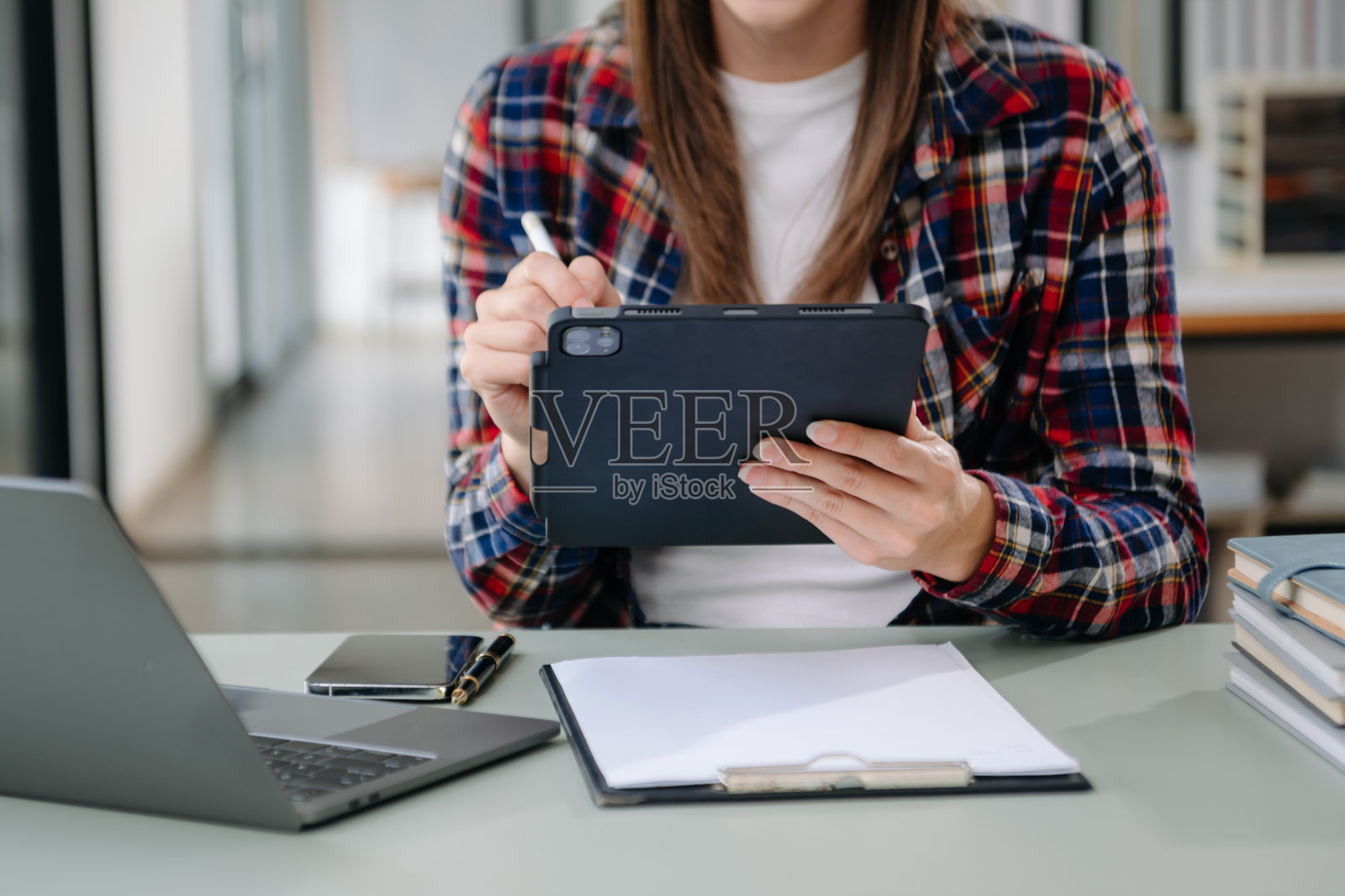 美丽的女人坐在她的工作场所使用笔记本电脑和平板电脑。集中照片摄影图片