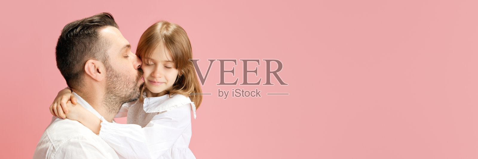 横幅。父亲亲吻他可爱的小女儿，粉色粉彩背景，负空插入文字。国际幸福日的概念照片摄影图片