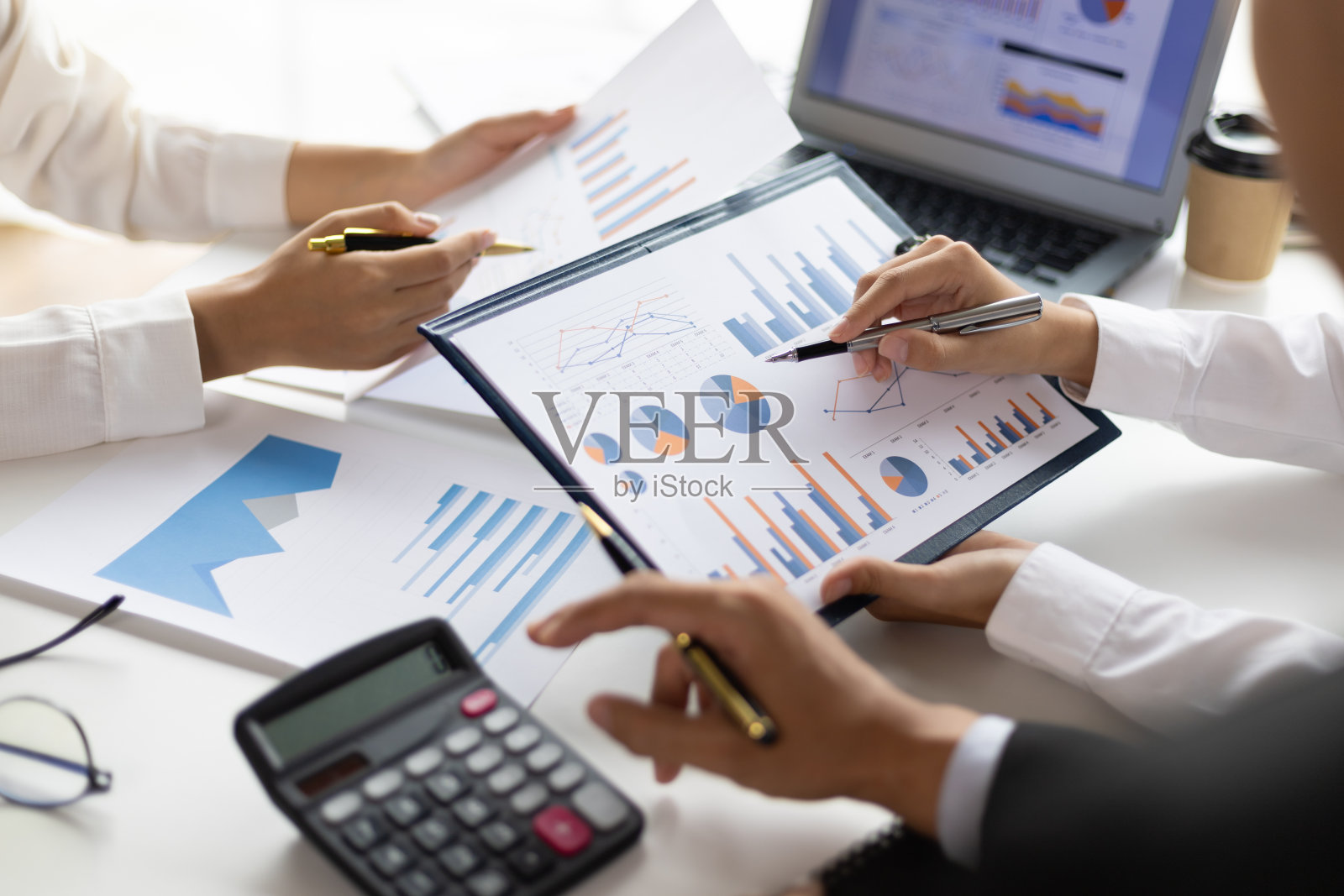 商务人士和同事一起集思广益，分析图表、财务报告和市场增长图表，制定新的商业投资策略。开会讨论统计分析。照片摄影图片