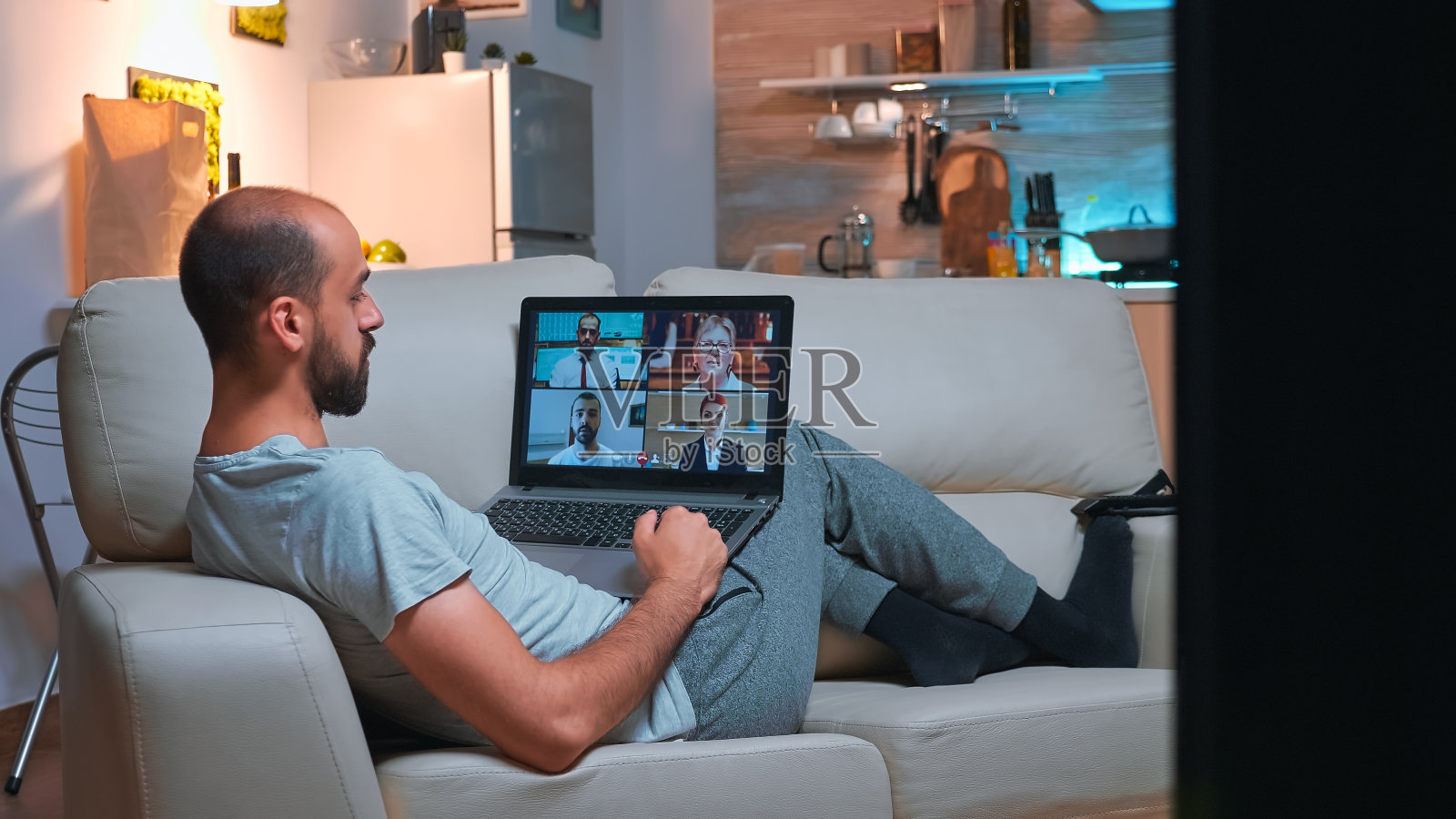 穿着睡衣的商人躺在沙发上和朋友聊天照片摄影图片