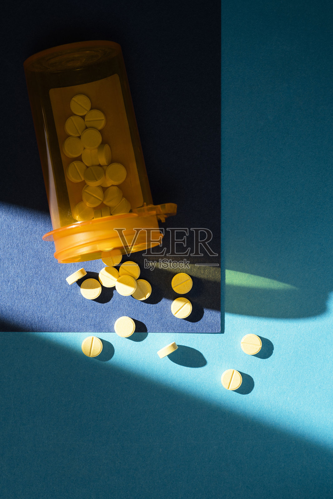 一瓶药片洒在蓝色的背景上照片摄影图片