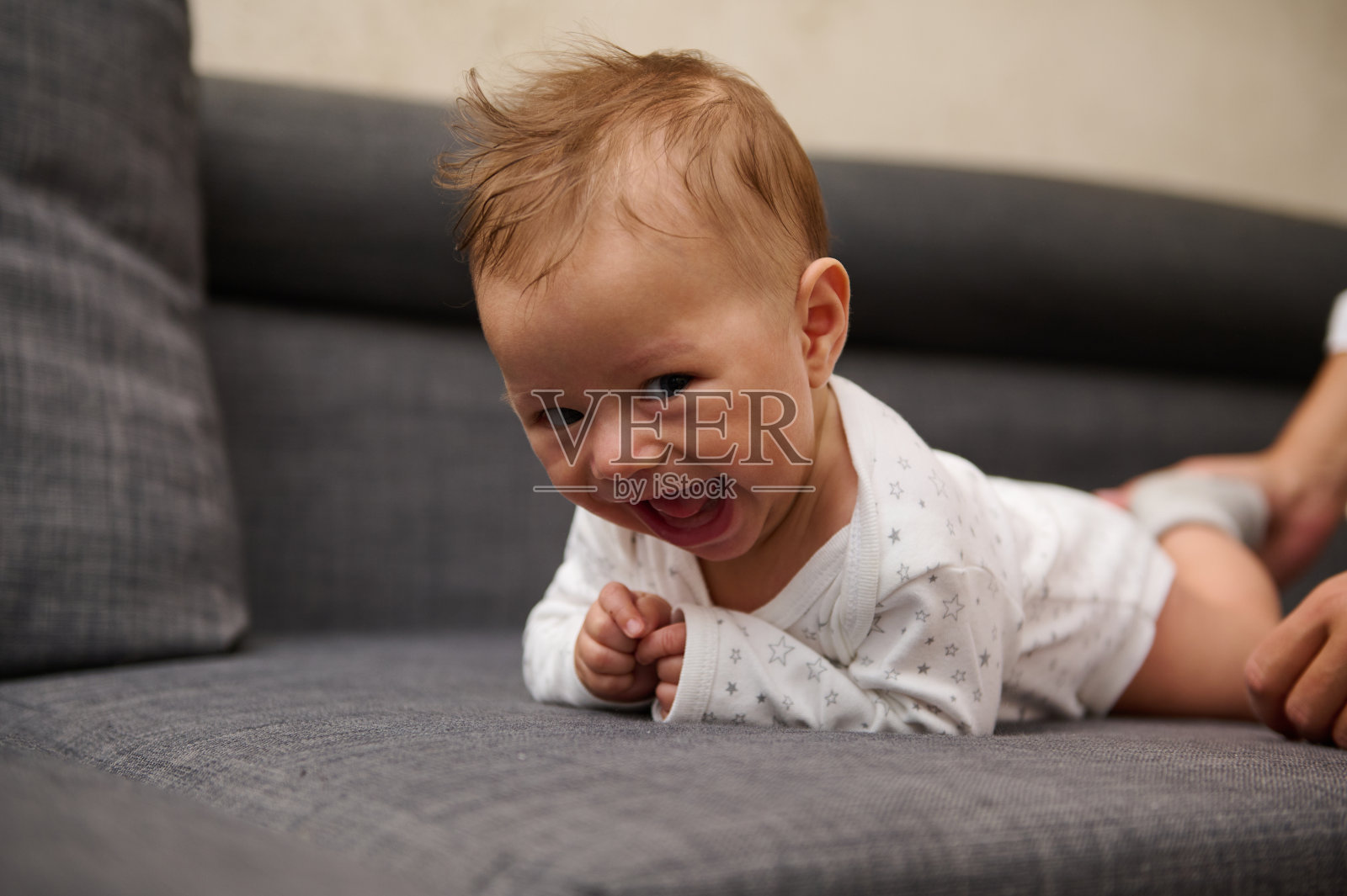 调皮开朗有趣的快乐小男孩5个月大，趴在家里的沙发上，看着镜头照片摄影图片