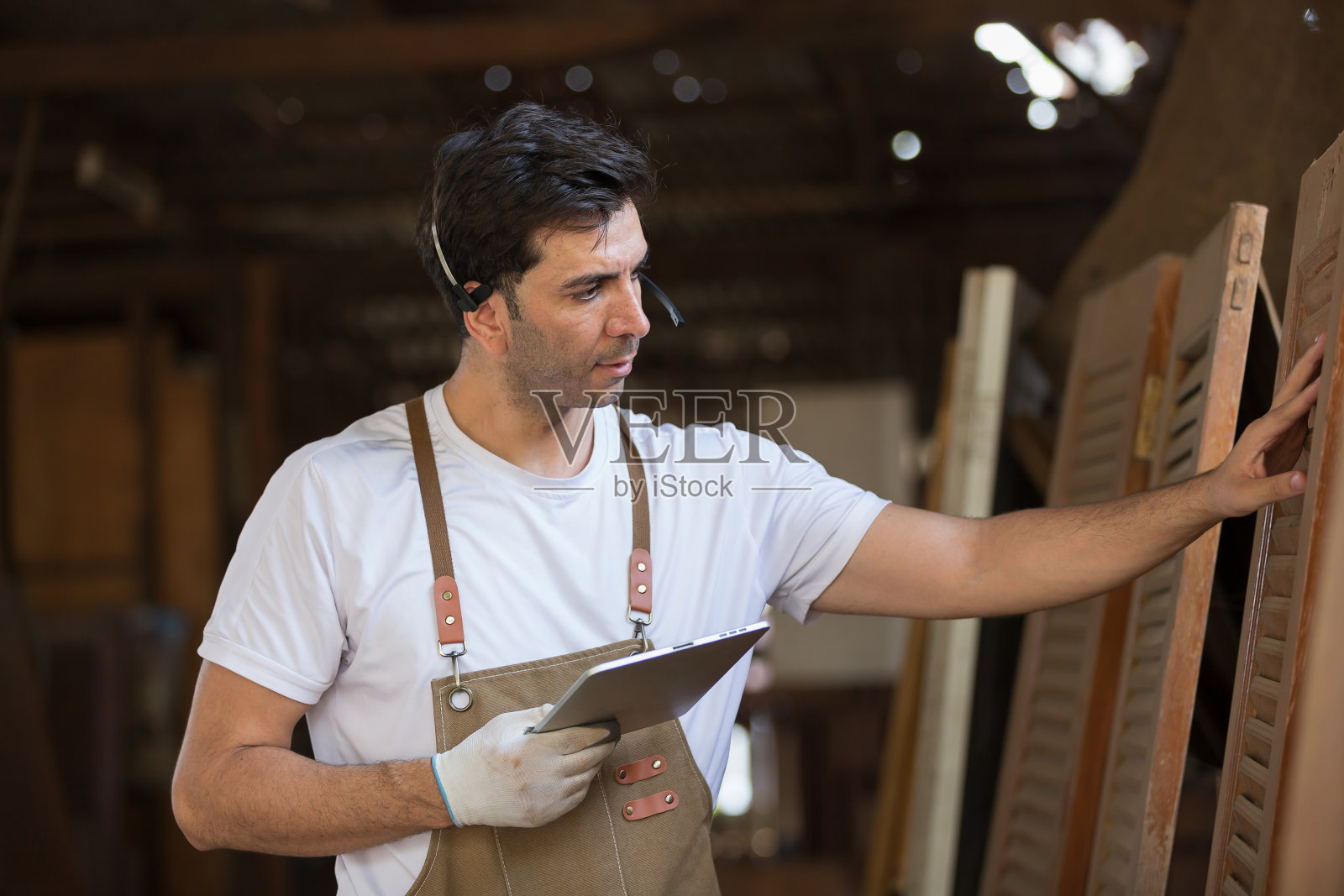 男木匠在木工车间用数码平板检查家具的肖像。在家具车间工作的男细木工。创业和小企业的概念照片摄影图片