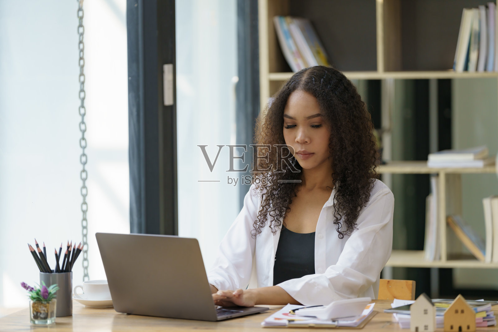 一个漂亮的非裔美国女孩、学生或女商人坐在办公桌前。照片摄影图片