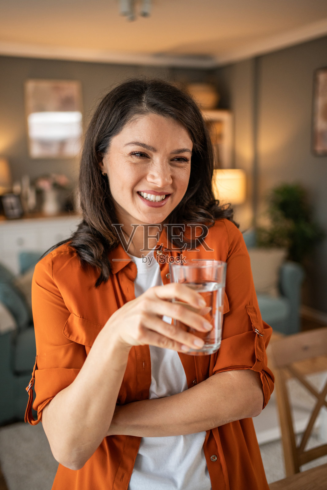 一个微笑的女人拿着一杯新鲜干净的饮用水的画像。健康生活方式和液体摄入的概念照片摄影图片