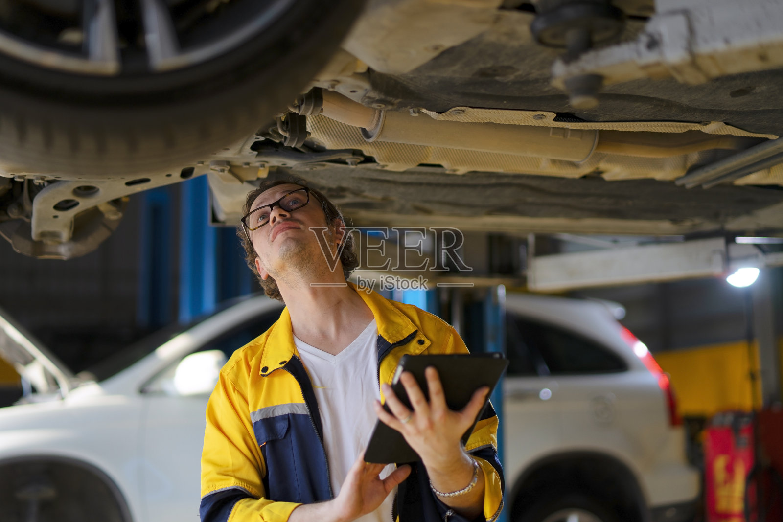 蓝领工人在汽车维修车间工作。照片摄影图片