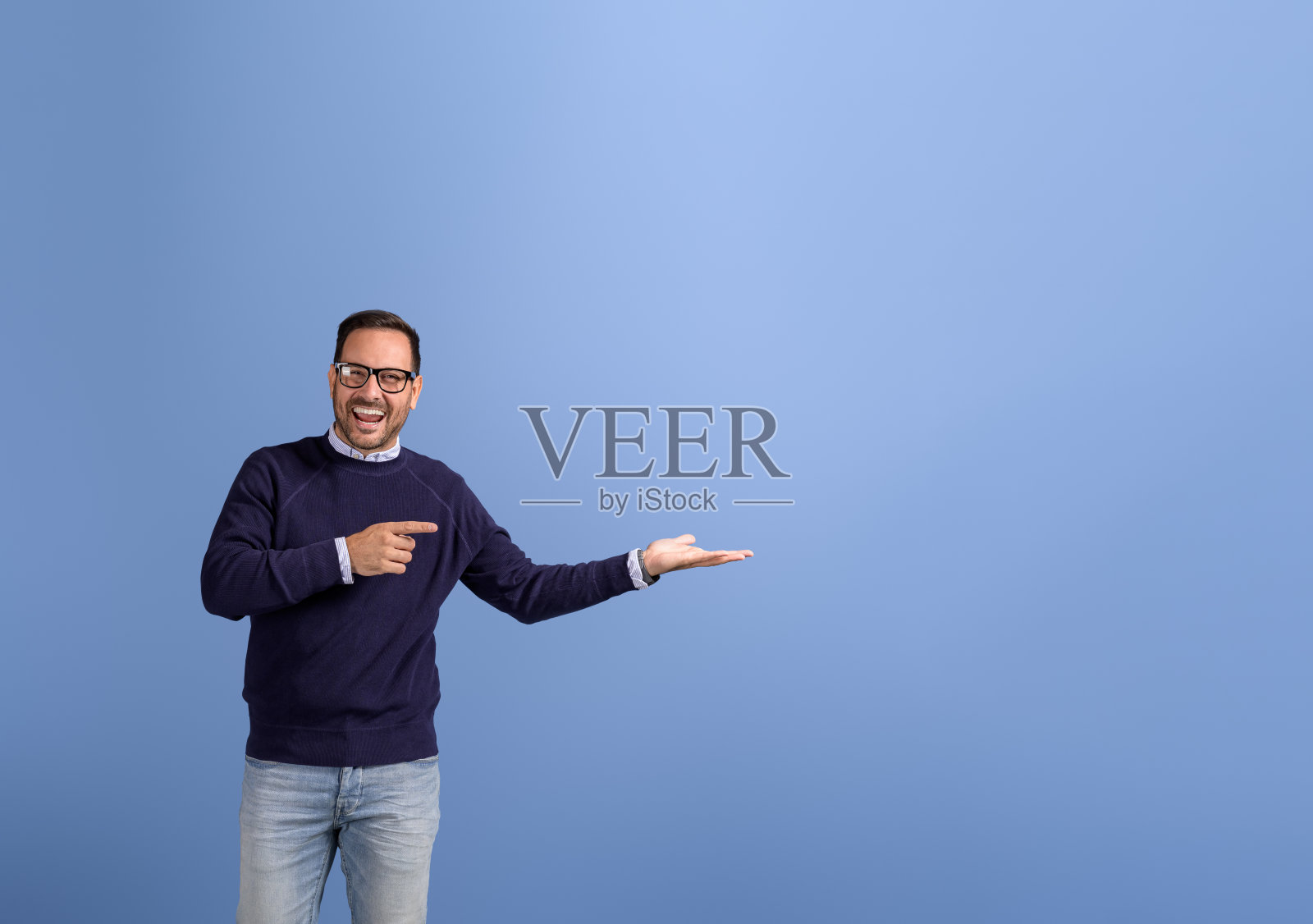 在蓝色背景上推销新产品时，欣喜若狂的推销员指着并展示空手照片摄影图片