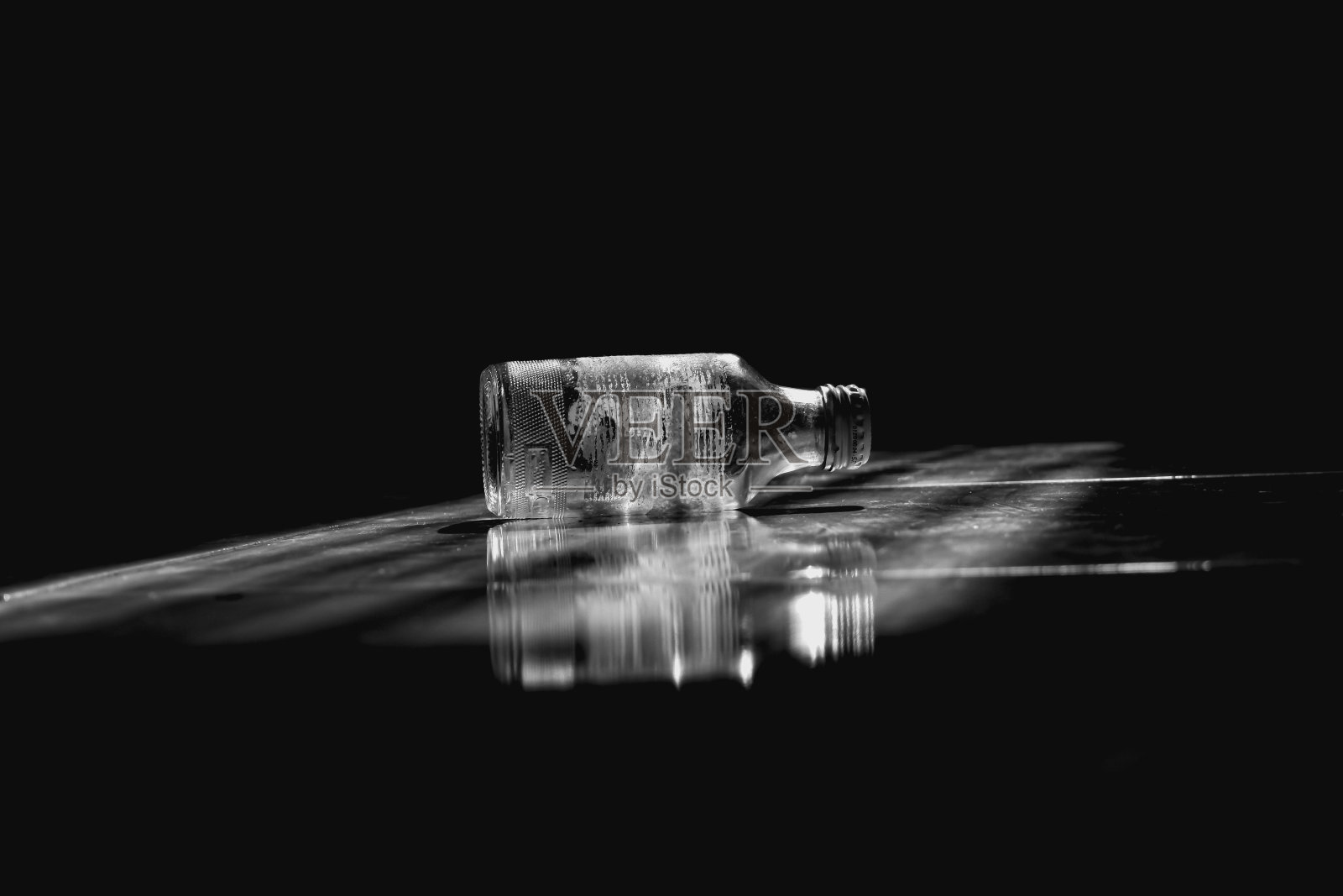 一个空玻璃瓶躺在地板上，垃圾玻璃瓶在地板上低光照片摄影图片