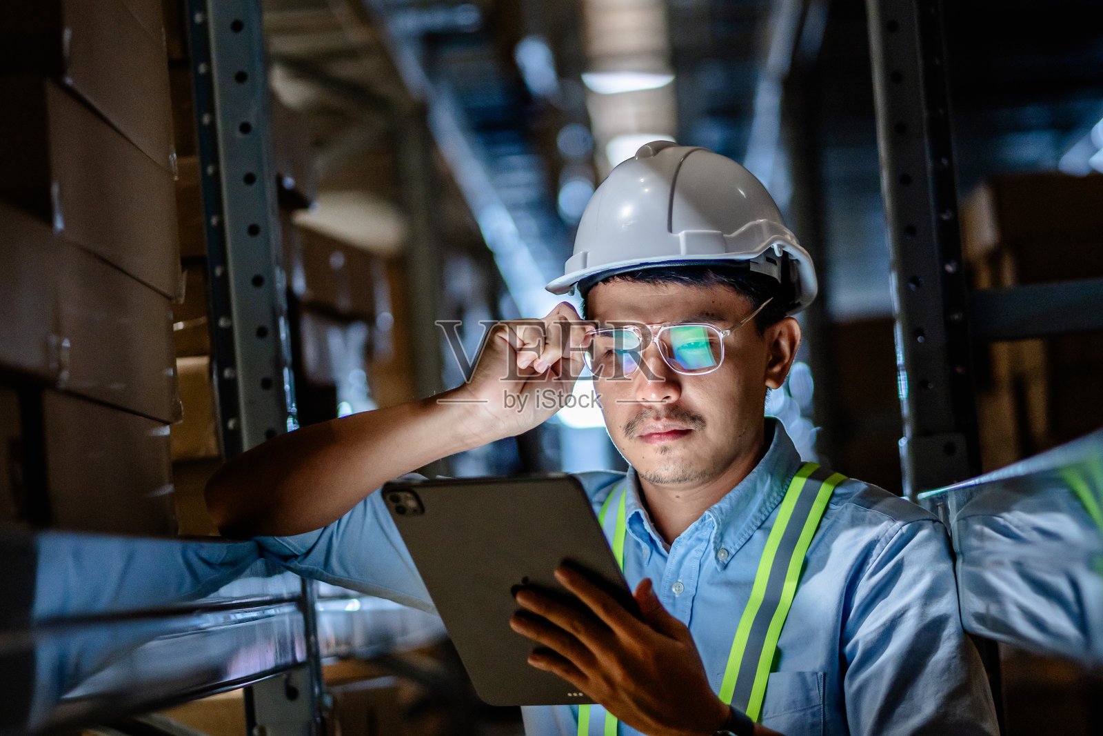 商人或经理使用数字平板电脑查看大型仓库货架上的库存，智能仓库管理系统，供应链和物流网络技术概念。照片摄影图片