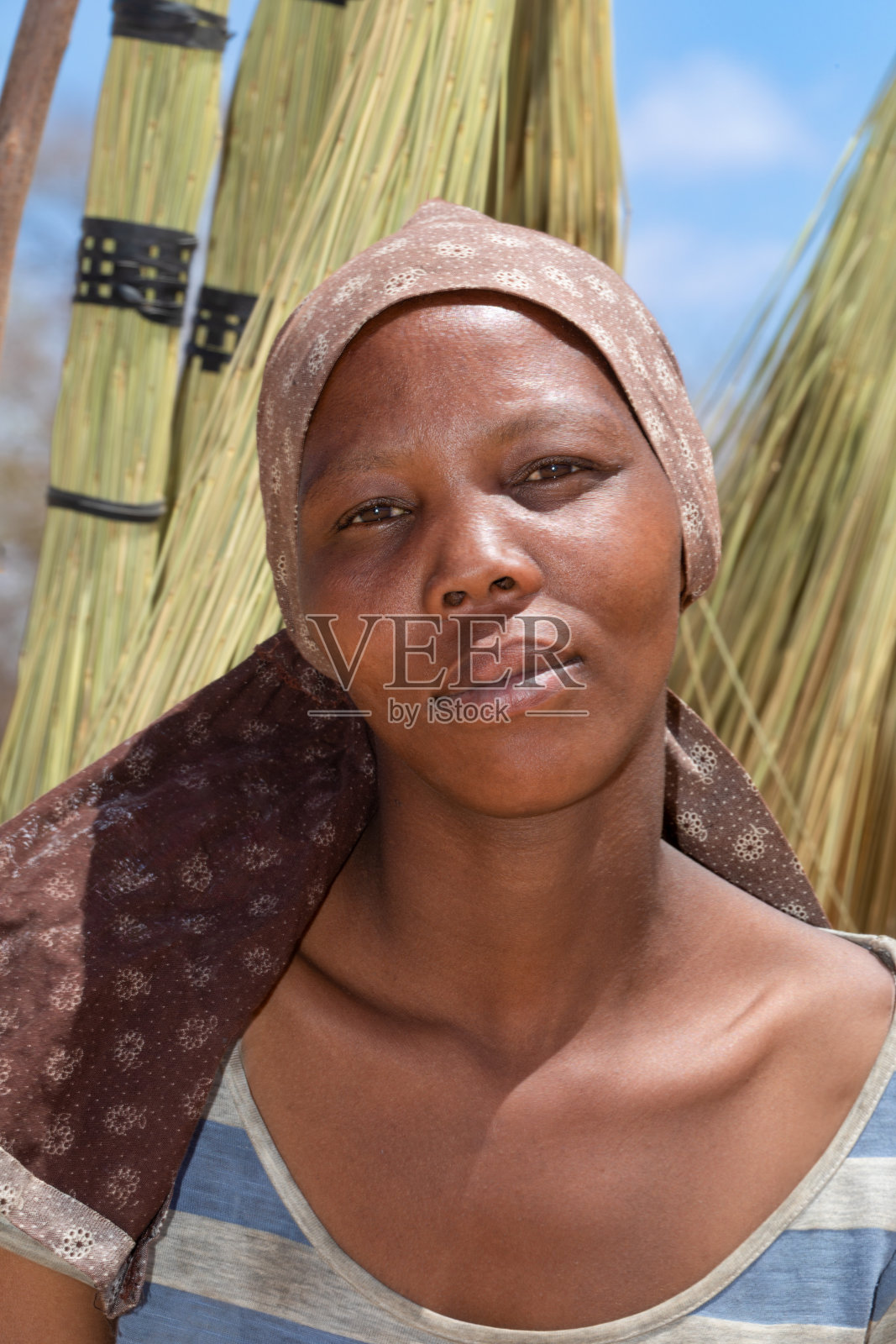 在一个阳光明媚的日子里，一个年轻的非洲妇女站在一个扫帚架前照片摄影图片
