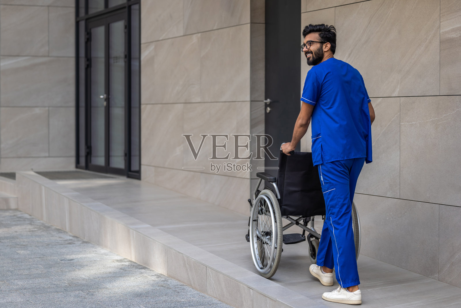医院院子里一个高个子黑发男人推着轮椅照片摄影图片