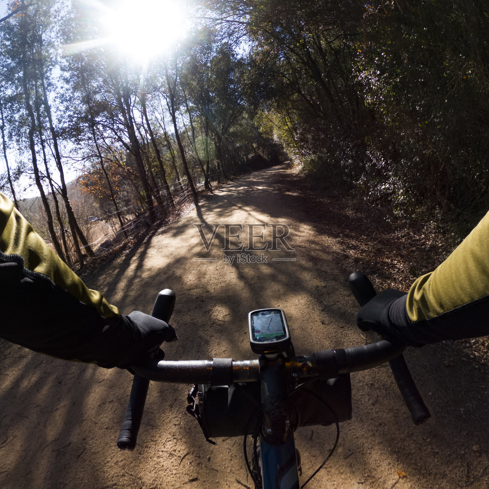骑着一辆弯弯曲曲的砾石自行车，在树林间的砾石小道上，阳光透过树枝照进来照片摄影图片