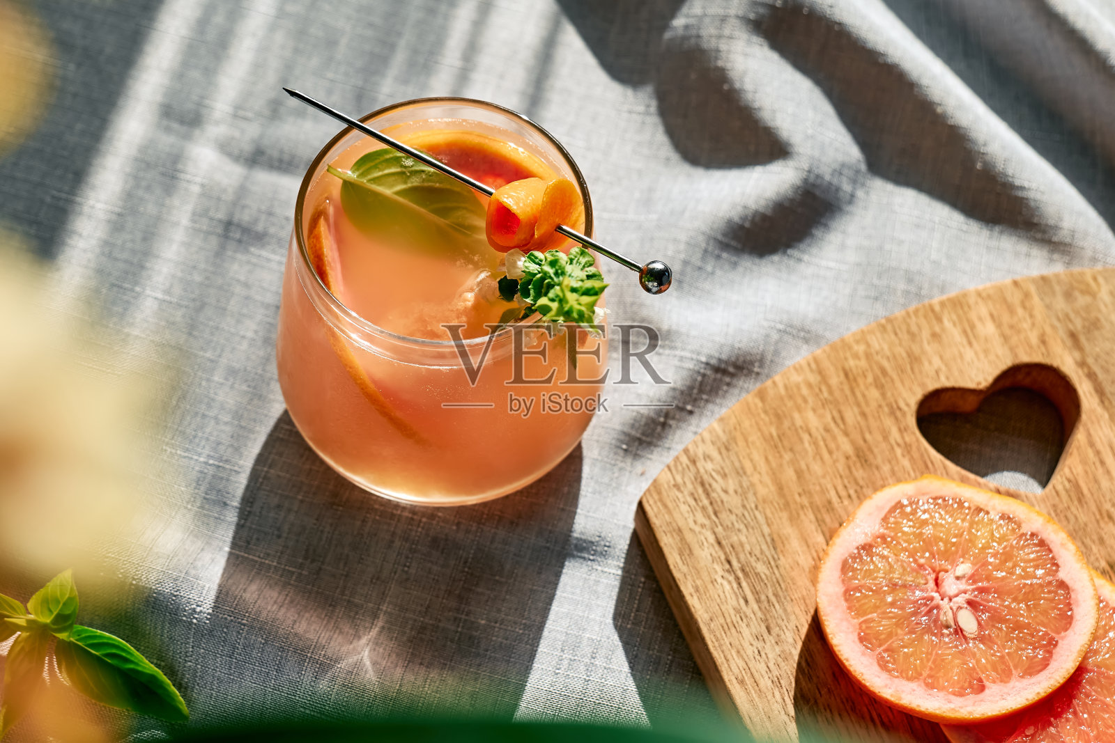 夏季清爽的葡萄柚饮料或葡萄柚片，冰和香草的酒精鸡尾酒。柑橘排毒饮料。照片摄影图片