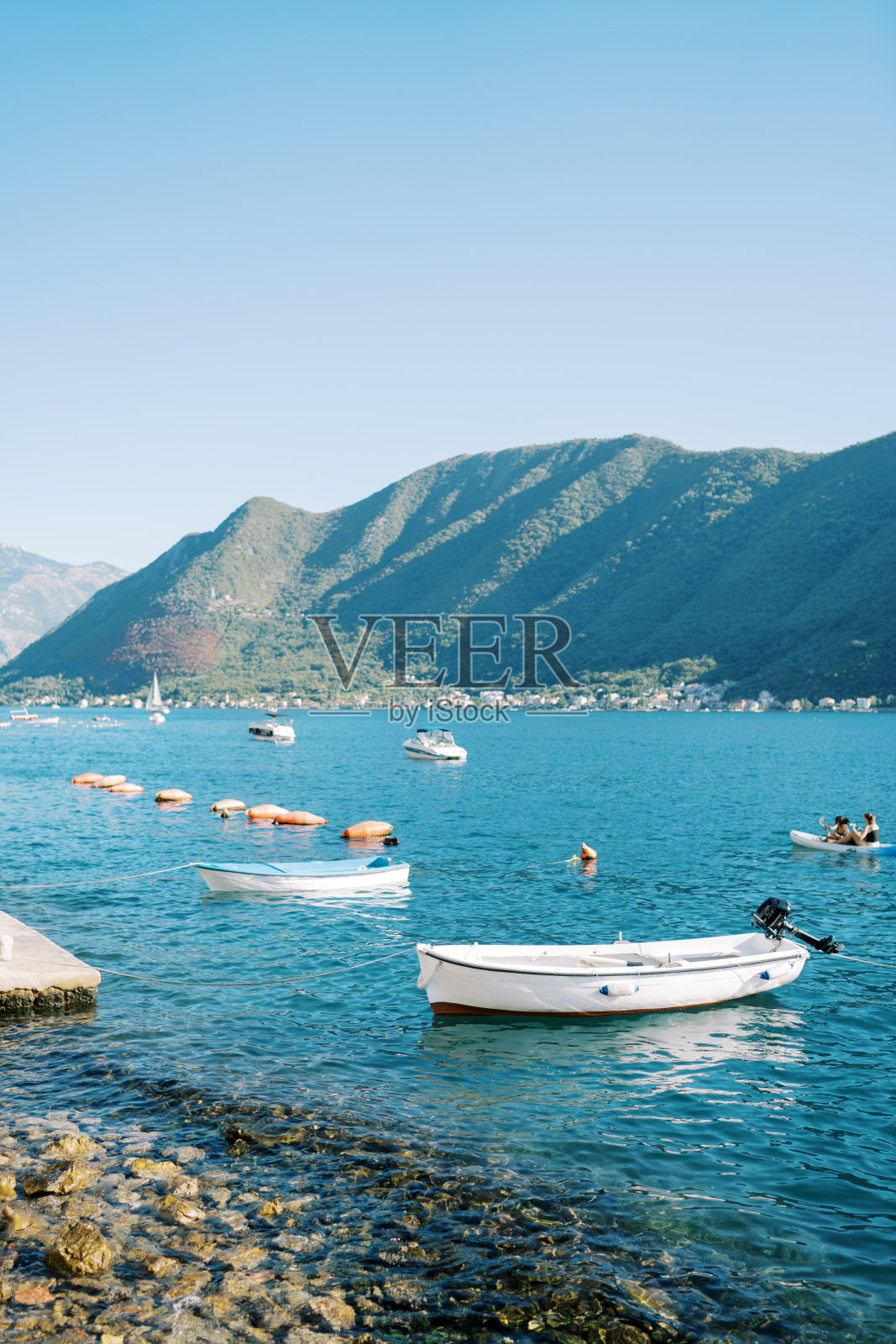 渔船在群山的映衬下矗立在海岸外照片摄影图片