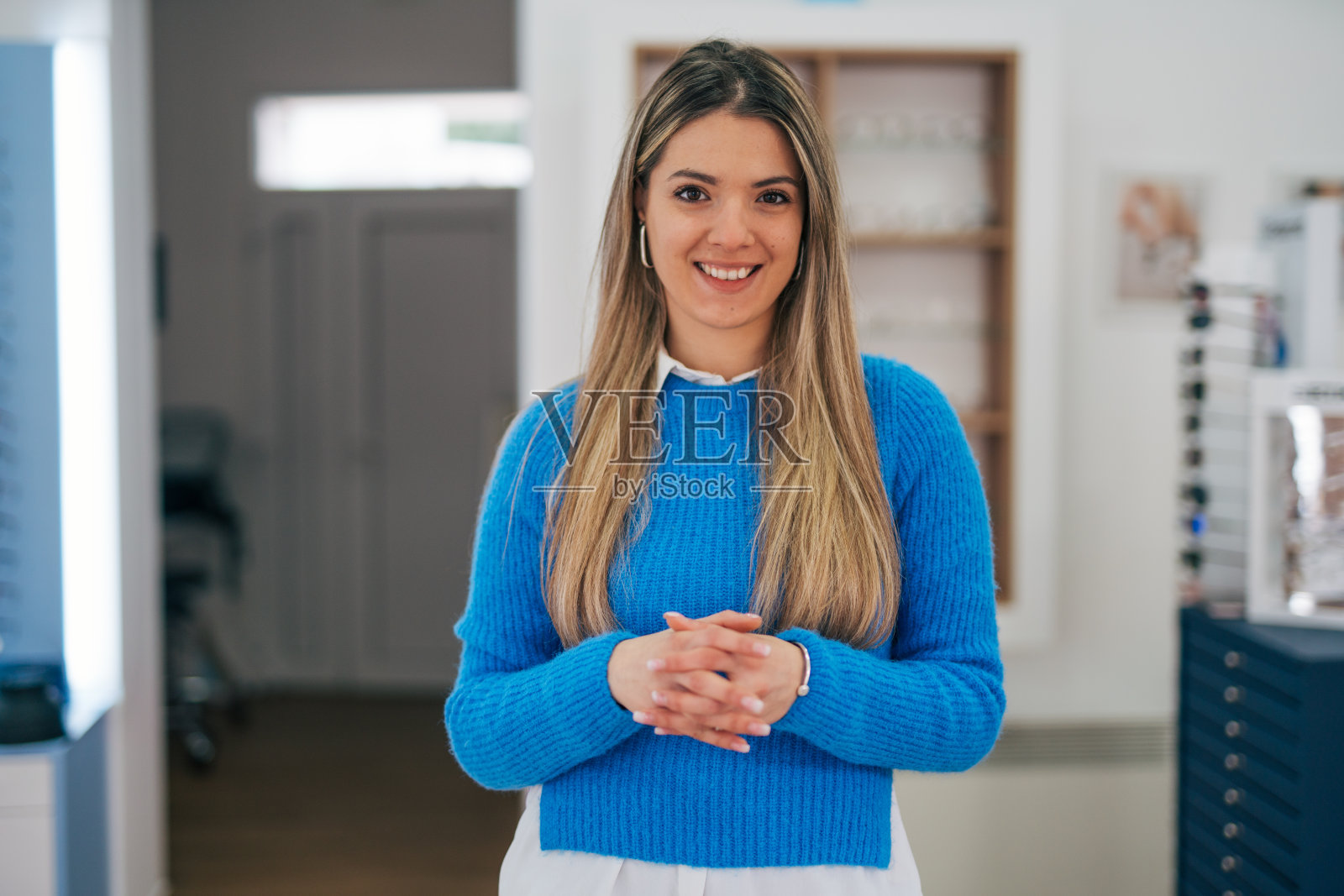 一个穿着蓝色毛衣的年轻女子的肖像，双手合十。照片摄影图片