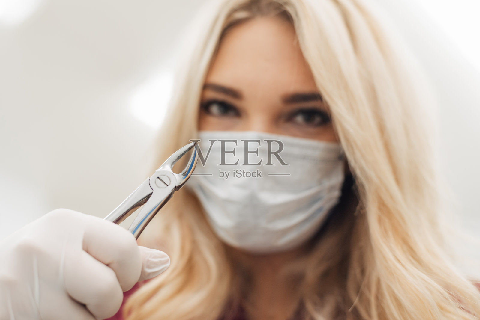 在诊所里，牙医手里拿着外科钳子，拔除一颗蛀牙照片摄影图片