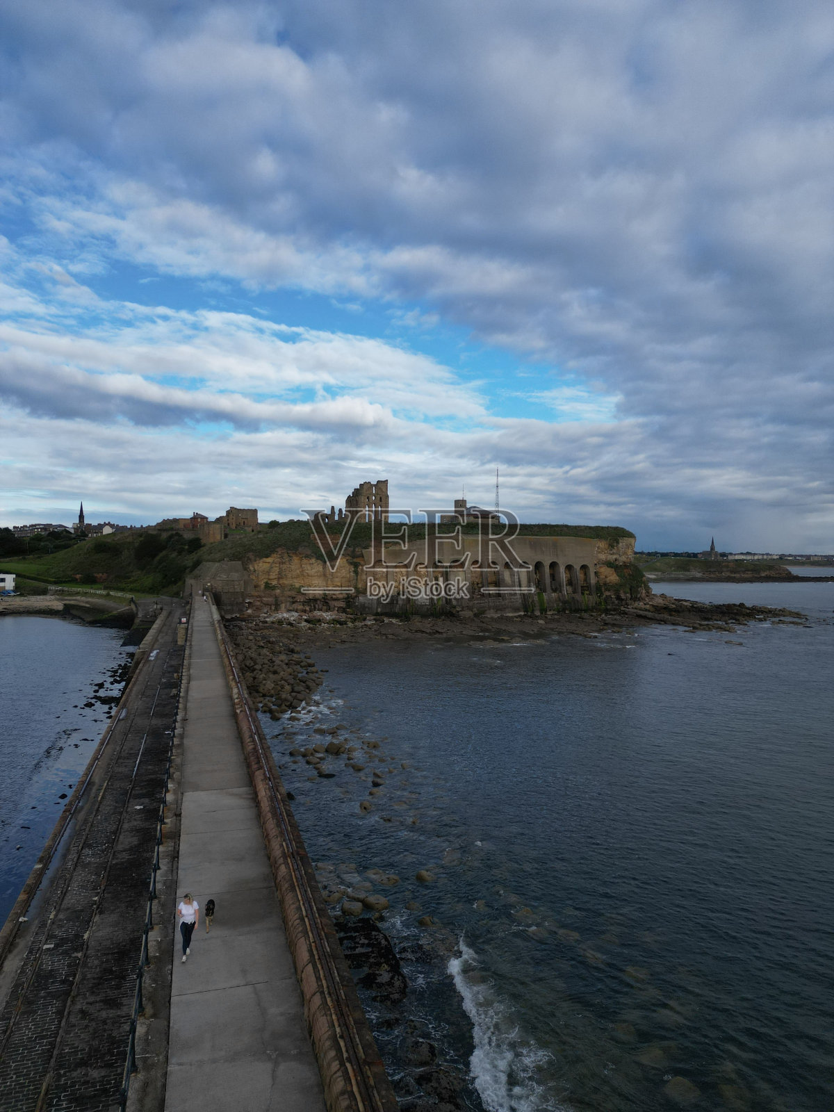 阴天的码头上，人们走过码头照片摄影图片